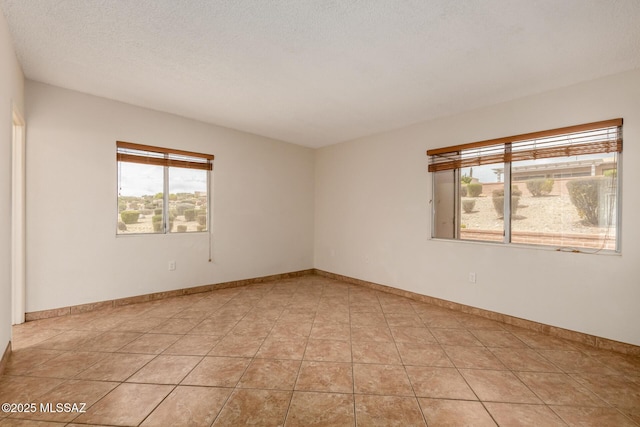 unfurnished room with baseboards, a textured ceiling, and light tile patterned floors
