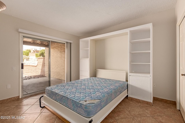 bedroom featuring a textured ceiling, access to exterior, baseboards, and tile patterned floors