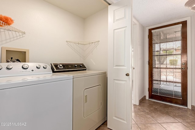 laundry room with light tile patterned flooring, a textured ceiling, laundry area, and washer and dryer