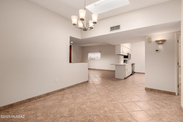 interior space featuring baseboards, light tile patterned flooring, a skylight, visible vents, and a notable chandelier