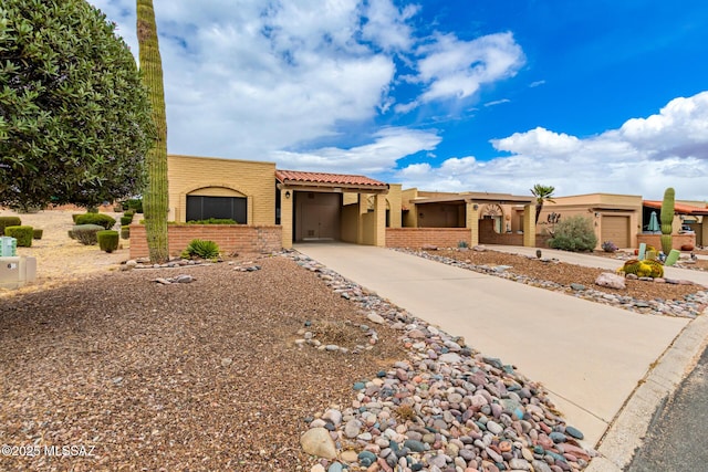 southwest-style home featuring stucco siding, brick siding, and concrete driveway