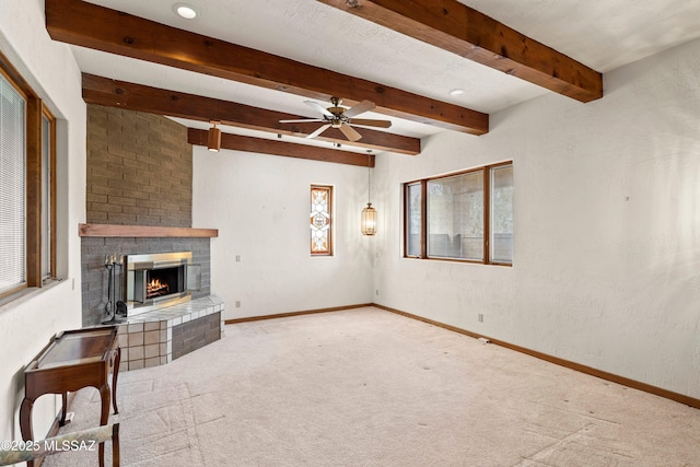 unfurnished living room featuring beam ceiling, a fireplace, ceiling fan, carpet, and baseboards