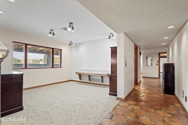 empty room with a textured ceiling, visible vents, recessed lighting, and baseboards
