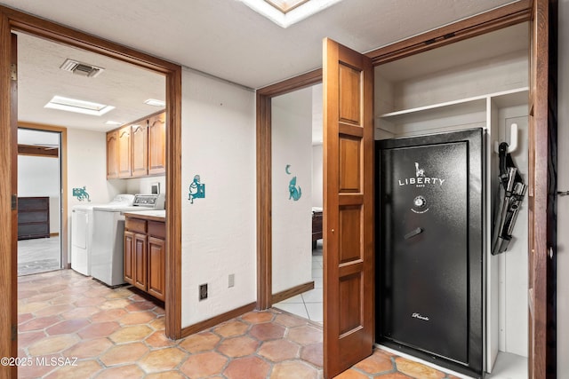 kitchen featuring washing machine and clothes dryer, visible vents, light countertops, baseboards, and light tile patterned flooring