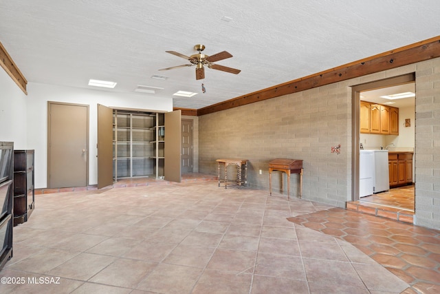 interior space with light tile patterned floors, a ceiling fan, a textured ceiling, and brick wall