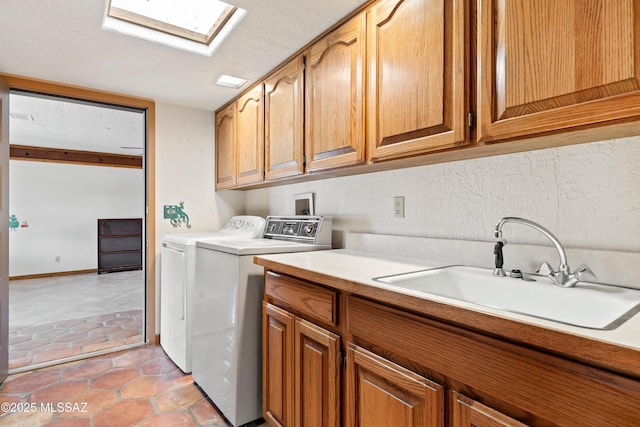 laundry room featuring a sink, a skylight, cabinet space, and independent washer and dryer