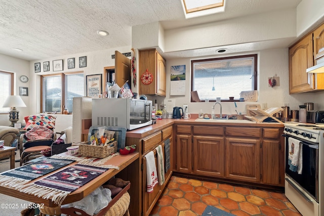 kitchen featuring white range with electric cooktop, a textured ceiling, a sink, and a healthy amount of sunlight