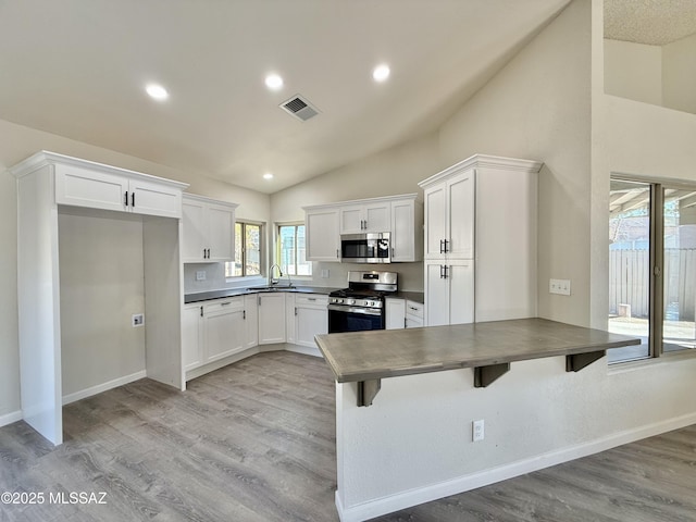 3438 Avenida Del Pueblo, Tucson, AZ 85746 - kitchen with a peninsula, dark countertops, vaulted ceiling, visible vents, and appliances with stainless steel finishes