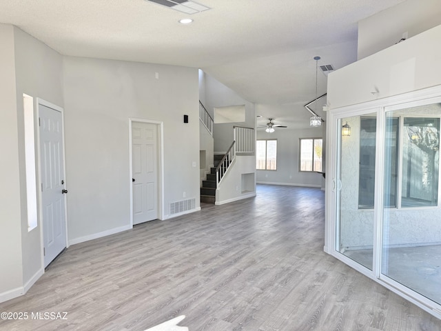3438 Avenida Del Pueblo, Tucson, AZ 85746 - empty room with wood finished floors, visible vents, a ceiling fan, stairs, and high vaulted ceiling