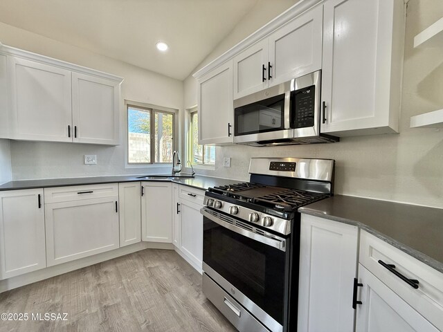 3438 Avenida Del Pueblo, Tucson, AZ 85746 - kitchen featuring white cabinets, lofted ceiling, a sink, light wood-style floors, and appliances with stainless steel finishes