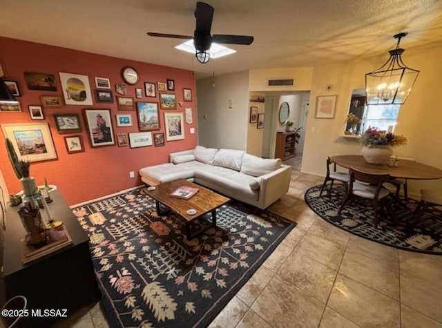 living room with tile patterned flooring, visible vents, and ceiling fan with notable chandelier
