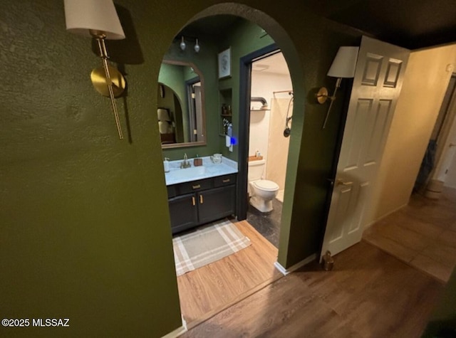 bathroom with toilet, vanity, and wood finished floors