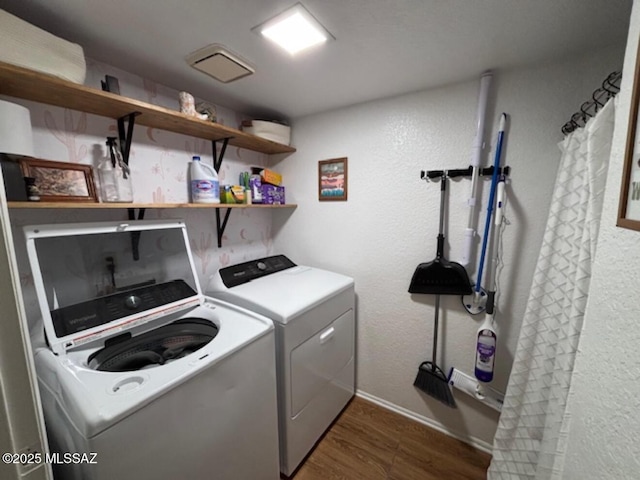 washroom with laundry area, dark wood finished floors, washer and dryer, a textured wall, and baseboards