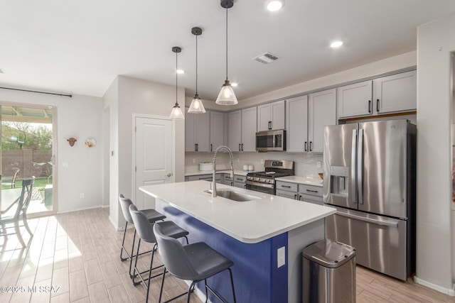 kitchen featuring gray cabinets, a sink, stainless steel appliances, and visible vents