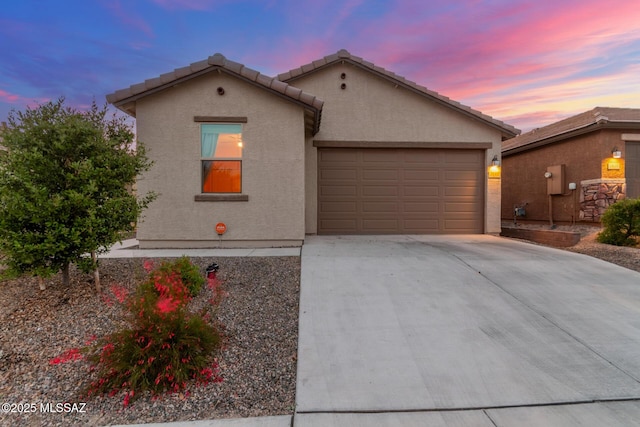 mediterranean / spanish house with a tiled roof, driveway, stucco siding, and an attached garage
