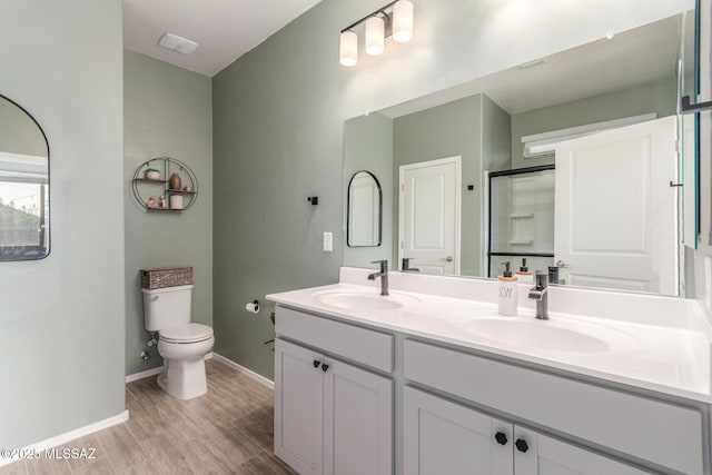full bath featuring toilet, a sink, a stall shower, and wood finished floors