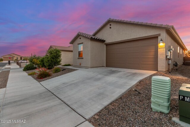 view of front of house with driveway, stucco siding, a garage, and a tiled roof
