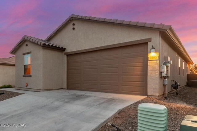 view of property exterior with driveway, stucco siding, and an attached garage