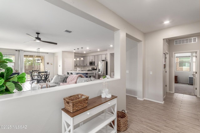 living room featuring ceiling fan, visible vents, recessed lighting, and light wood finished floors