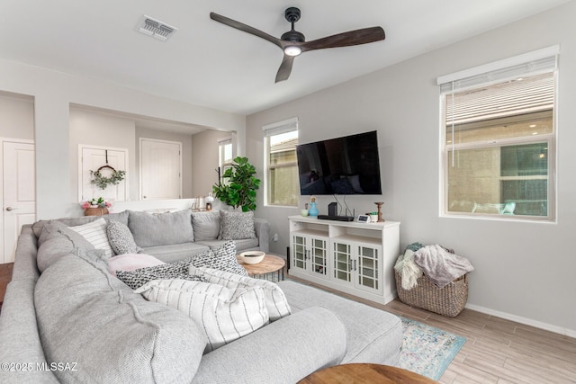 living area with wood finished floors, baseboards, ceiling fan, and visible vents
