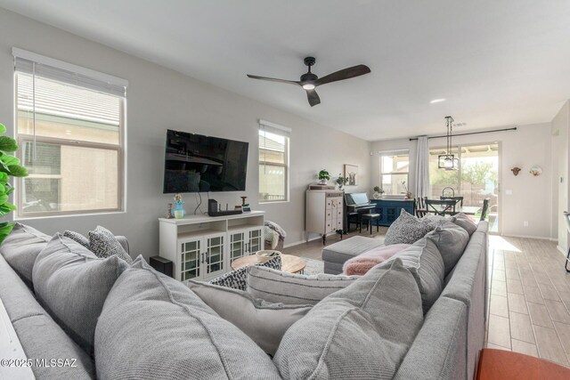 living room featuring baseboards, light wood-style flooring, and a ceiling fan