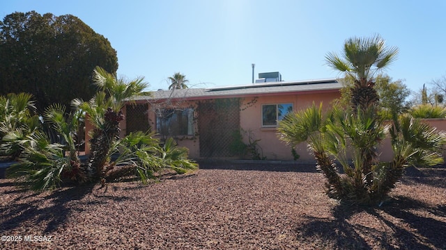 back of house with stucco siding and solar panels