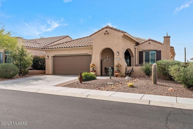 mediterranean / spanish home with stucco siding, a tiled roof, and concrete driveway
