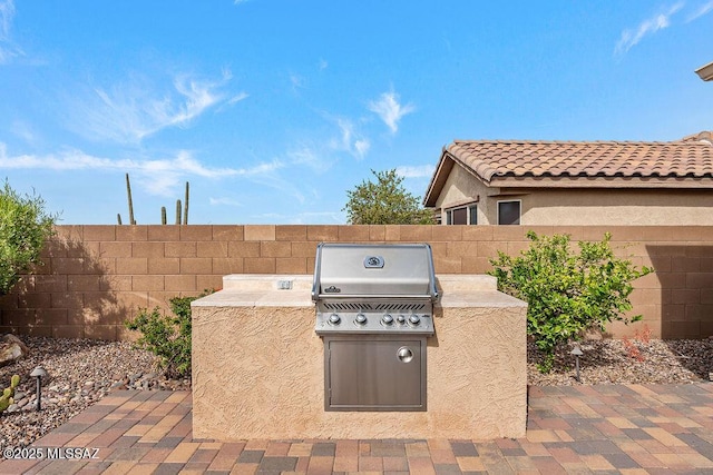 view of patio featuring a grill, exterior kitchen, and fence
