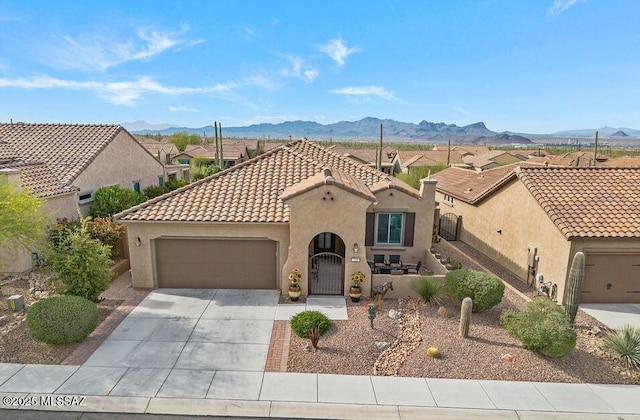 mediterranean / spanish house featuring stucco siding, driveway, a mountain view, and an attached garage