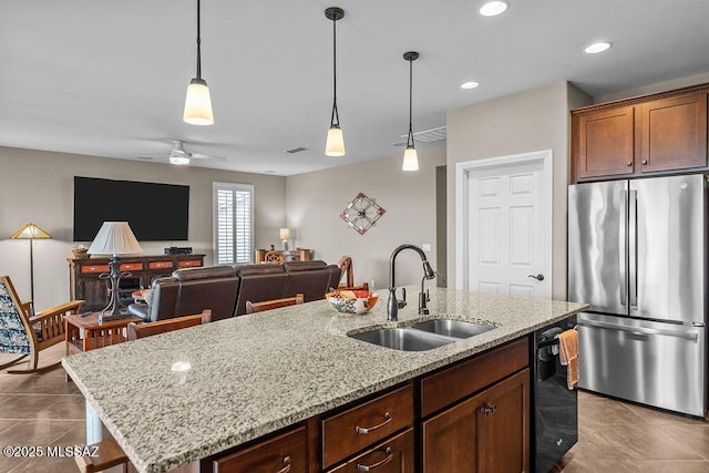 kitchen featuring a sink, freestanding refrigerator, hanging light fixtures, dishwashing machine, and a kitchen island with sink