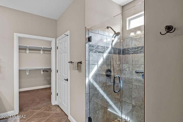 bathroom featuring a stall shower, baseboards, tile patterned flooring, and a spacious closet
