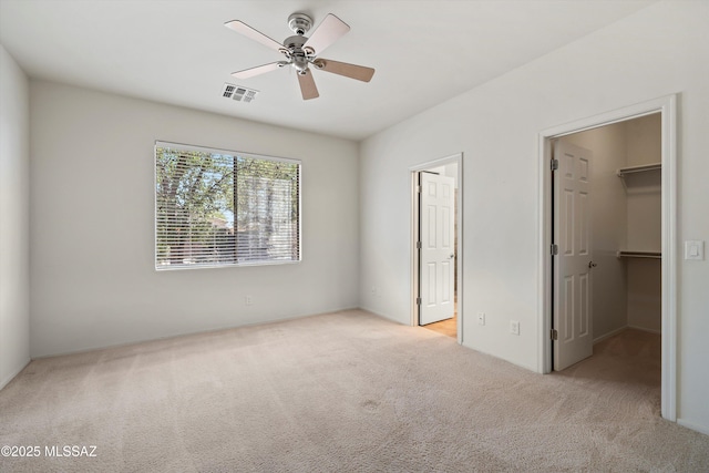 unfurnished bedroom with a spacious closet, carpet floors, a closet, ceiling fan, and visible vents