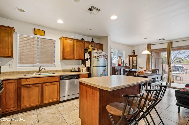kitchen featuring visible vents, a center island, a sink, appliances with stainless steel finishes, and a breakfast bar area