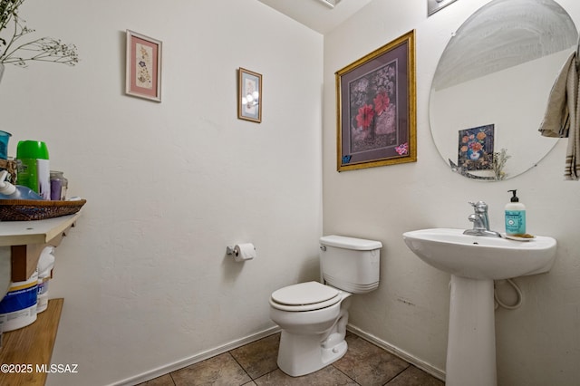 bathroom with toilet, baseboards, and tile patterned flooring