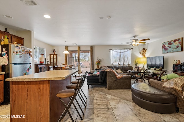 kitchen with a center island, open floor plan, light countertops, ceiling fan, and a kitchen bar