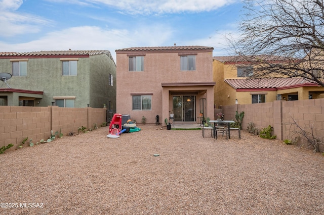 rear view of property with stucco siding, a patio area, a fenced backyard, a tiled roof, and a playground