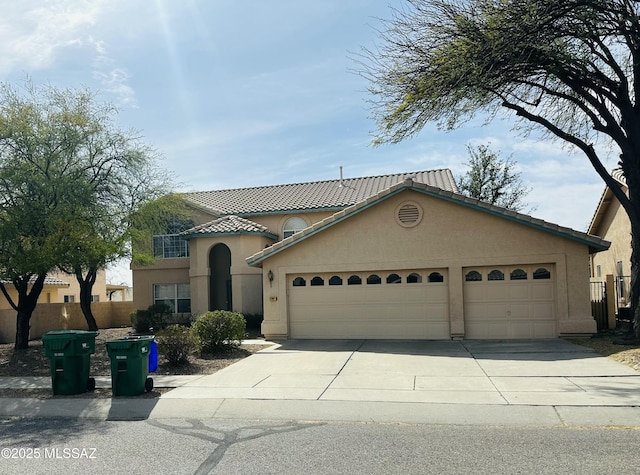 view of front of house featuring fence, an attached garage, a tile roof, stucco siding, and driveway