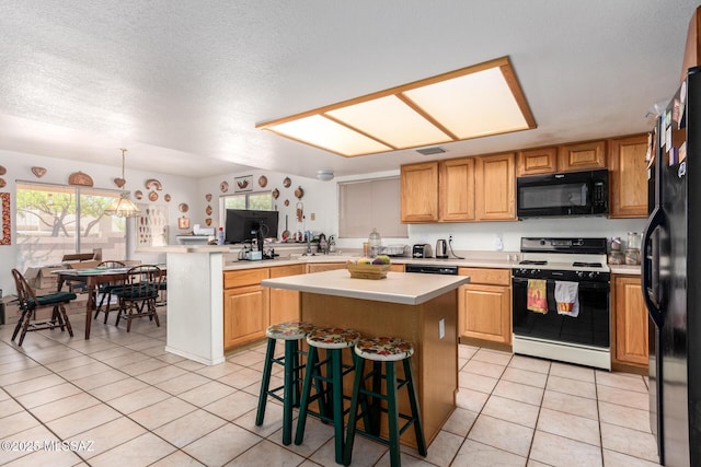 kitchen with light tile patterned flooring, a breakfast bar, light countertops, a center island, and black appliances