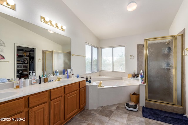 bathroom with a garden tub, double vanity, lofted ceiling, a sink, and a stall shower