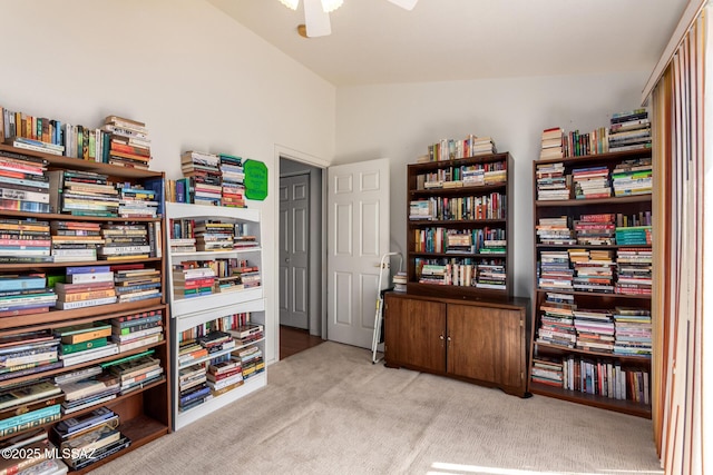 interior space featuring carpet floors, ceiling fan, vaulted ceiling, and bookshelves