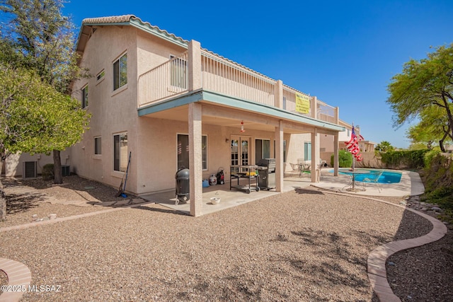 back of property featuring a fenced in pool, a balcony, a patio area, and stucco siding