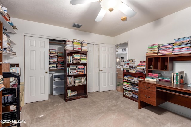 office space featuring visible vents, ceiling fan, and light colored carpet