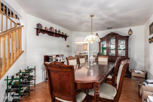 dining area featuring visible vents, stairs, wood finished floors, and a chandelier
