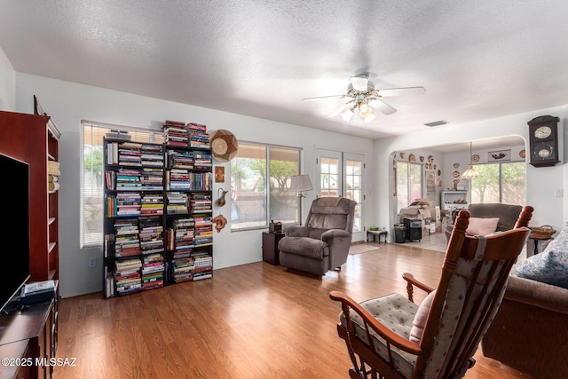 living room featuring a ceiling fan, visible vents, and wood finished floors