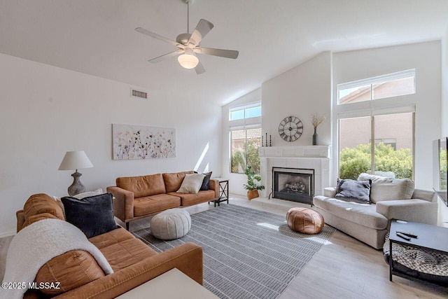 36526 S Wind Crest Dr, Tucson, AZ 85739 - living room with high vaulted ceiling, a tiled fireplace, light wood-style flooring, visible vents, and ceiling fan