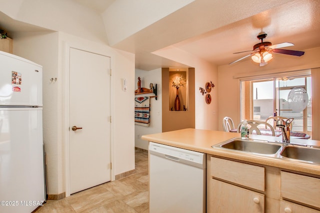 kitchen featuring light countertops, a sink, a ceiling fan, light brown cabinets, and white appliances