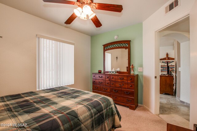 bedroom featuring light carpet, visible vents, arched walkways, and ceiling fan