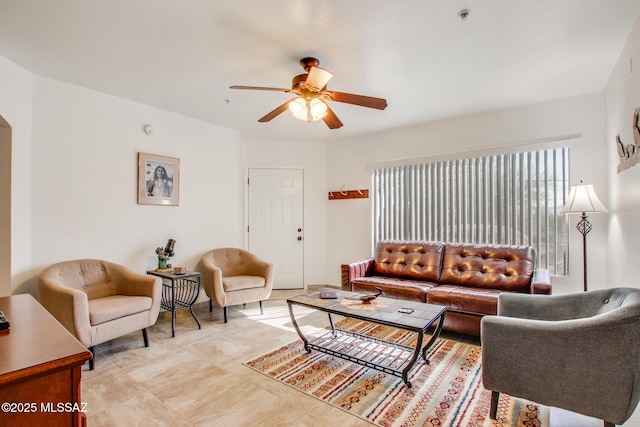 living area featuring arched walkways and ceiling fan