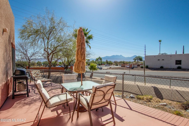 view of patio / terrace featuring outdoor dining space, area for grilling, fence, and a mountain view