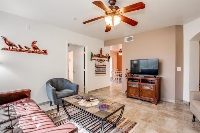 living room with arched walkways, baseboards, visible vents, and a ceiling fan